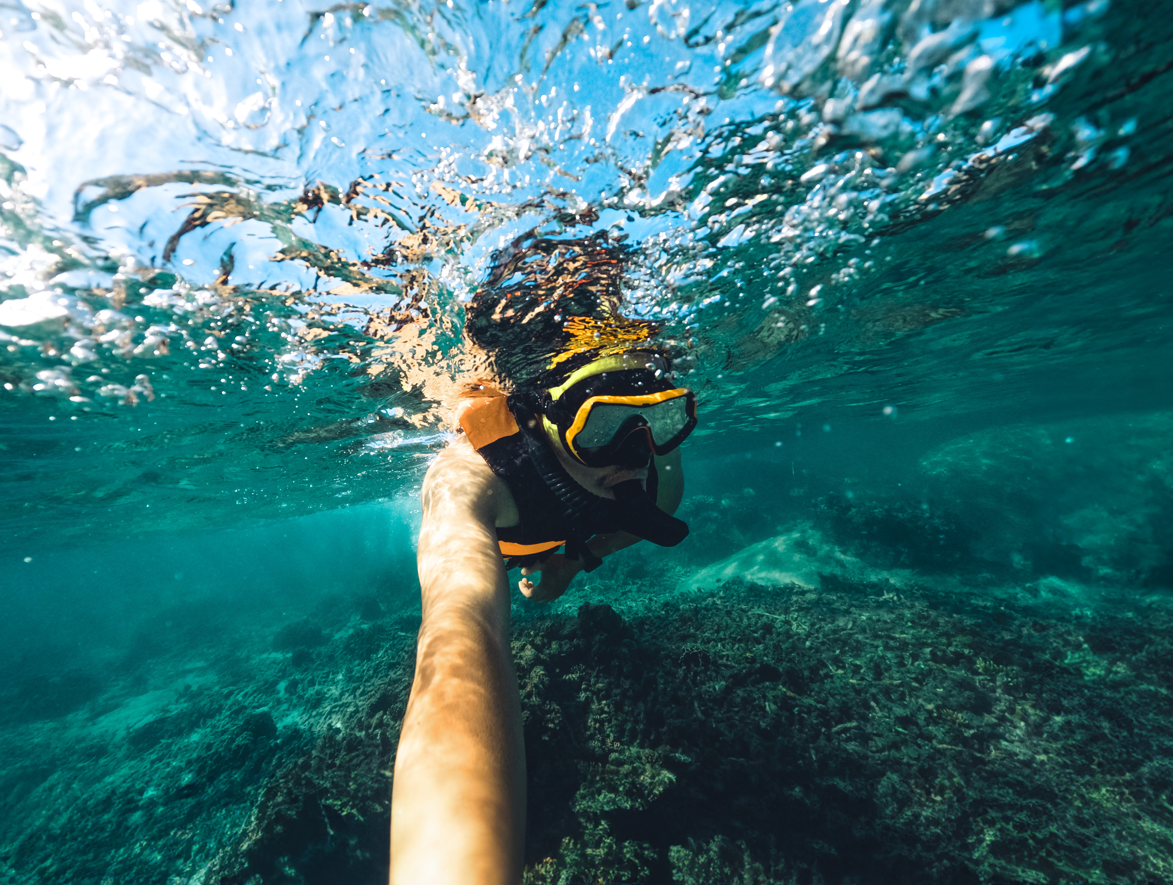 Pessoa a mergulhar num mar cristalino, a simbolizar o lema da campanha de verão do Poupança no Minuto: O verão é seu, o trabalho é nosso.